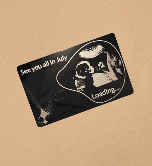 Card anunț sarcină cu imagine stilizată de ecografie și text „See you all in July – Loading…” pe fundal negru